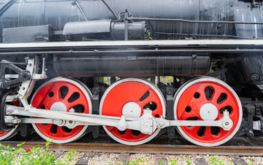 Red wheels of a steam train locomotive are seen on the train station railway