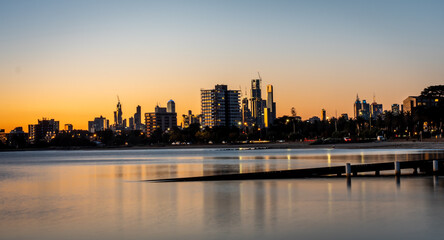 The reflections of the melbourne city skyline at dusk in the still water at st kilda beach