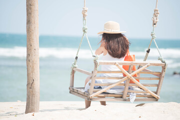 A woman sitting on a swing And looking at the sea on the beach