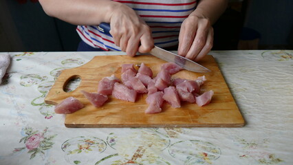 cook cuts raw meat with a knife