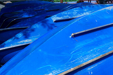 A row of bright blue rowboats on the shore