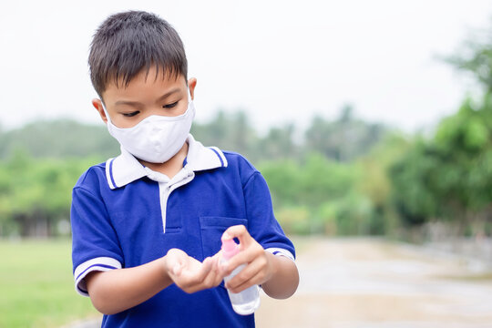 Young Asian child boy wearing fabric mask and holding Alcohol spray bottle in his hand for prevent Corona virus or Covid-19 disease. Washing and cleaning hand by Alcohol gel. Health care and kid.
