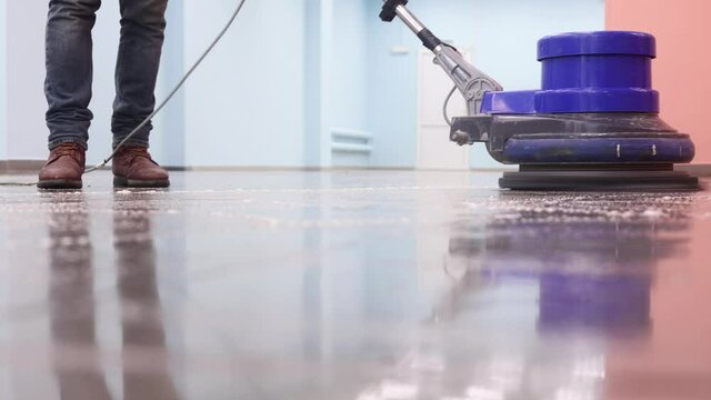 the cleaner washes a pier with a professional polisher machine. Cleaning floor in office building lobby