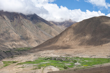 Aerial view of the village in a greenfield valley in front of mountain range in Kashmir, Northern India.