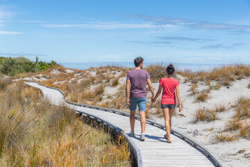 Couple walking on beach holding hands romantic in New Zealand - young people in Ship Creek on West...