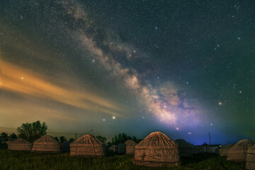 Under the bright Milky Way, Mongolia yurts on the grassland are scattered.