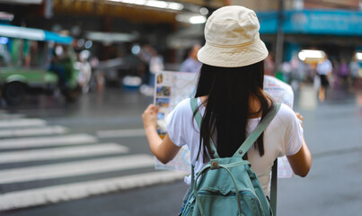 Traveler backpack Asian woman looking on map in the street , back view.