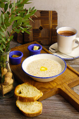 Tasty breakfast of oatmeal, a cup of cocoa, bread, butter and jam on a gray background