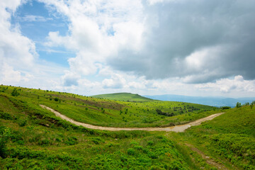 Fototapeta premium path through mountain landscape. road through green rolling hills. cloudy weather