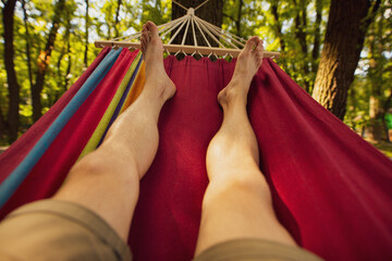 Male legs chill out lying on hammock