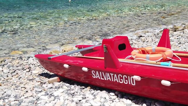SLOW MOTION: red lifeguard rowing boat in Fenicia beach of Elba island in Italy. SALVATAGGIO meaning RESCUE in Italian.