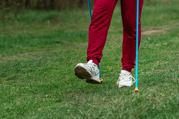 Nordic walking, sticks, legs close-up. The concept of a healthy lifestyle, cardio training. Copyspace.