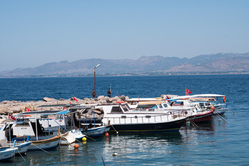 Fototapeta na wymiar Dikili,İzmir / Turkey - July,25 2019 Boats moored on the jetty,man fishing with rod