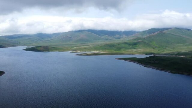 Aerial Drone shot of Lake, surrounded by hills and mountains. One of the biggest crystal pure water reservoirs in the world, located in Armenia, Caucasus.