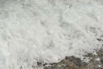 average waves on the sea reach the shore with foam and crash on the rocks with a noise