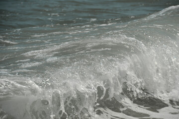 average waves on the sea reach the shore with foam and crash on the rocks with a noise