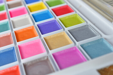 A close up image of a brand new water color paint set in a white plastic case. 