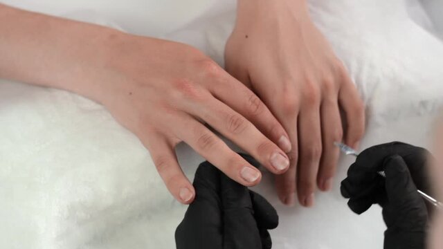 Nail technician using a sharp blade to smooth down and polish a clients nails