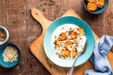 Breakfast bowl with grilled apricots with natural yoghurt, walnuts, almonds and thyme. Wodden background.