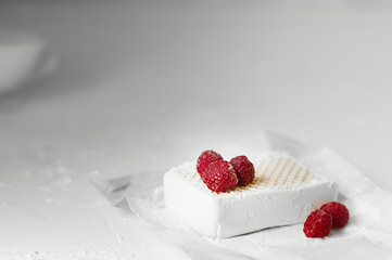 Obraz na płótnie Canvas rectangular piece of homemade white milk ice cream with fresh red berries of ripe raspberries on a light table. homemade seasonal easy recipes