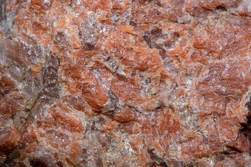 Background with the surface of a piece of red granite interspersed with quartz in soft focus under high magnification