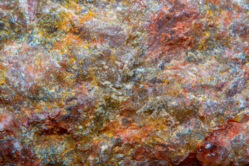 Fototapeta na wymiar Background with the surface of a piece of red granite interspersed with quartz in soft focus under high magnification