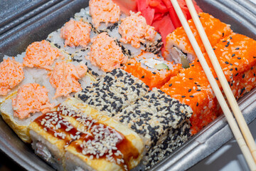 Background with a set of Japanese rolls in plastic packaging for delivery