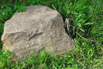 .A large decorative stone lies on the green grass.