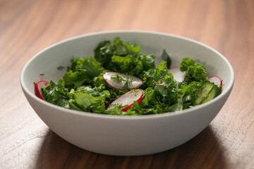 Summer fresh salad with radish, cucumber and herbs in white bowl