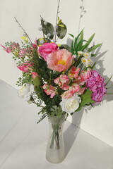 Bouquet of artificial flowers in a vase. A white background. Bergen, Netherlands, February 12, 2020.    