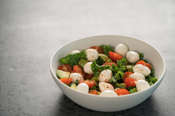 Salad with avocado, tomatoes and mozzarella in white bowl