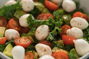 Salad with avocado, tomatoes and mozzarella closeup