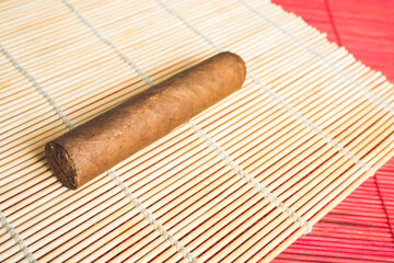 Unlit cigar on white bamboo mat.