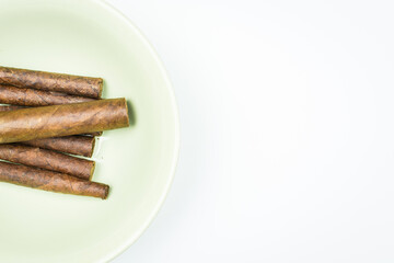 Excellent cigars from twisted sheets on plate with white background.