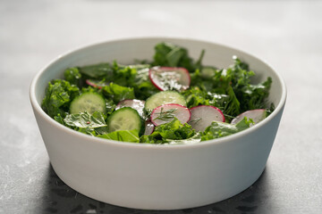 Summer fresh salad with radish, cucumber and herbs in white bowl