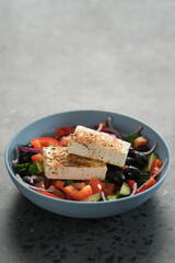 Traditional greek salad in blue bowl on concrete background with copy space