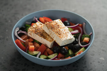 Traditional greek salad in blue bowl on concrete background