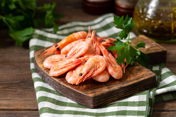 Shrimp on a wooden Board on a brown wooden table. Lots of prawns on the serving Board. Prawns close up