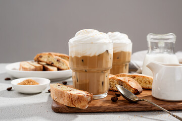 Iced coffee latte with whipped cream and biscotti cookies in glass.