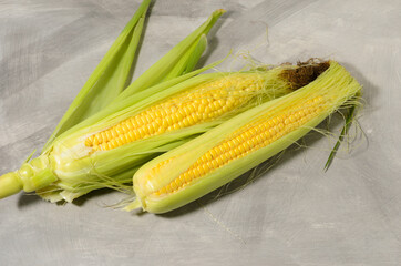 A ripe corn cob with leaves and yellow grains. Texture surface as a background.