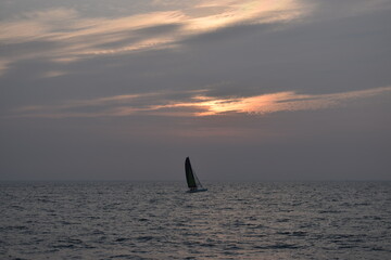 Fototapeta premium silhouette of a sailboat at sunset