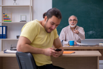 Old teacher and young male student in the classroom