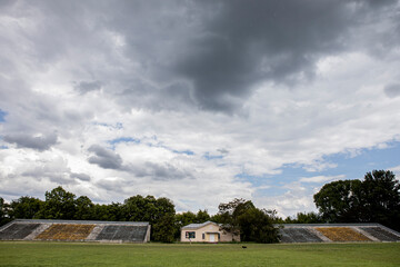 Fototapeta na wymiar football field with empty seats, green grass and cloudy sky