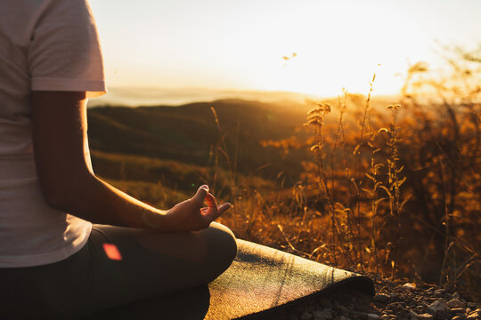 Woman hand in lotus position closeup. Zen meditation. Healthy lifestyle and yoga concept. Background of warm sunlight and mountain view. Empty place. - Powered by Adobe
