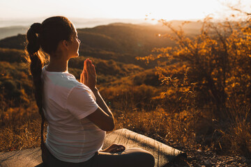 Spiritual and emotional concept of harmony with nature in maternity time. Pregnant woman praying...
