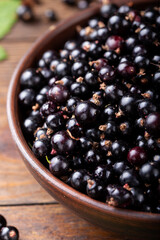 Black currants in the brown bowl .