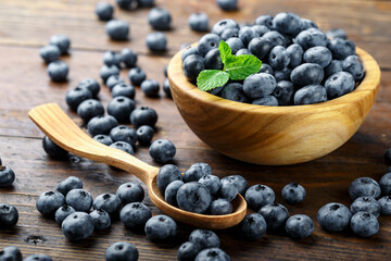 Freshly picked blueberries in wooden bowl on a wooden  table. Healthy fruits.
