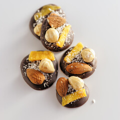 black chocolate with freeze dried berries and nuts handmade, natural on a white background, top view