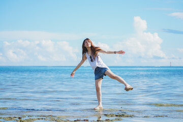 Fototapeta na wymiar 石垣島の海の波打ち際を歩く女性