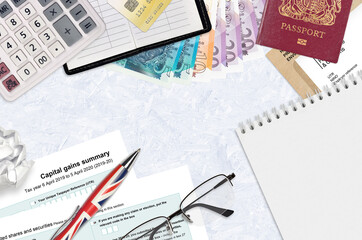 English Tax form sa107 Capital gains summary from HM revenue and customs lies on table with office...